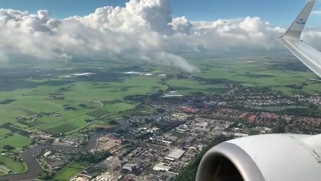 Uitzicht vanuit een KLM-toestel op de vleugel boven het Nederlandse polderlandschap
