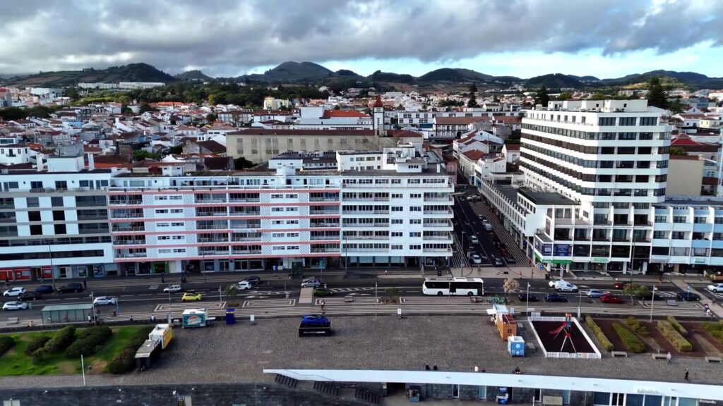 Luchtbeeld van de boulevard van Ponta Delgada op São Miguel met groene heuvels op de achtergrond, uit een video van SkyCruizer