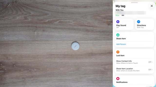 Een witte Smart Tag-tracker op een houten tafel naast de Zoek mijn-app met de optie om de locatie van een item te delen