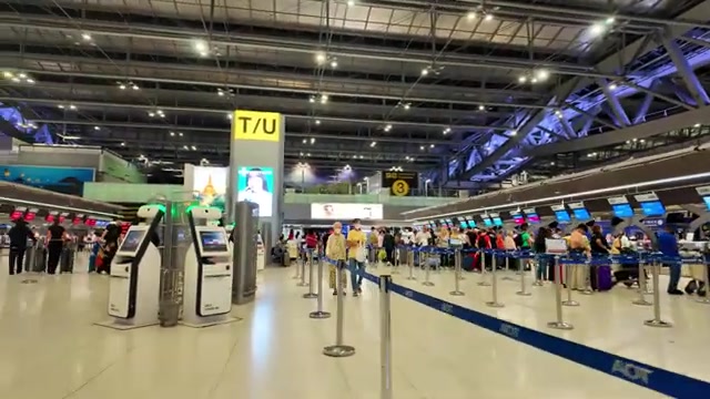 Incheckhal van luchthaven Suvarnabhumi in Bangkok met reizigers bij de balies, uit een video van DV Media Pattaya