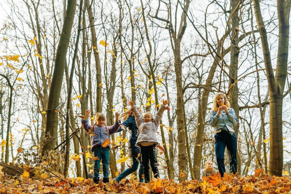 Gezin in regenjassen wandelt door een herfstbos met gele en oranje bladeren