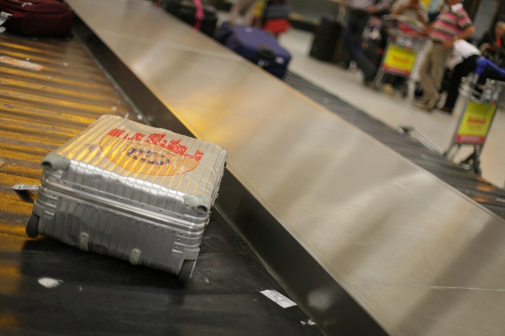 Reiziger met smartphone en koffer in de aankomsthal van een luchthaven