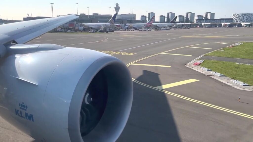 Motor van een KLM-toestel op Schiphol met de verkeerstoren op de achtergrond