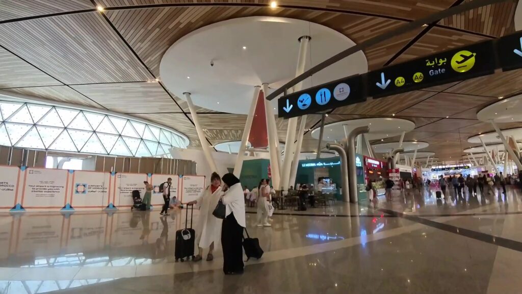 Vertrekhal van Marrakech-Menara met reizigers en borden naar de gates